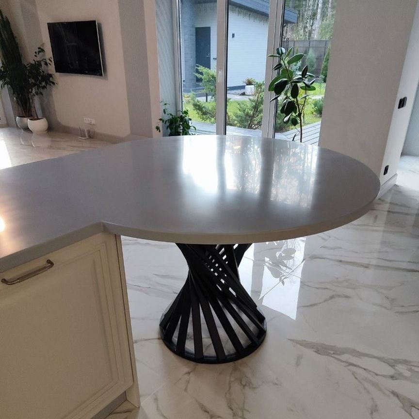 Островная столешница из акрилового камня светло-серого цвета с дизайнерской опорой в интерьере кухни