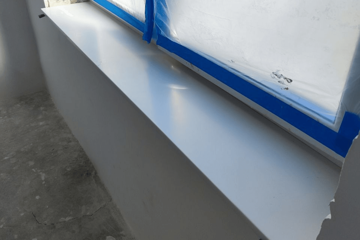 Белый подоконник из акрилового камня, установленный в новом помещении, окно подготовлено к отделке — этап чистового монтажа