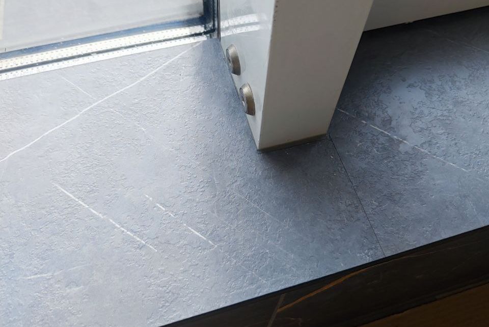 Подоконник из HPL компакт пластика серого цвета с обходом оконной рамы, выполненный с точной подгонкой, для современного интерьера.