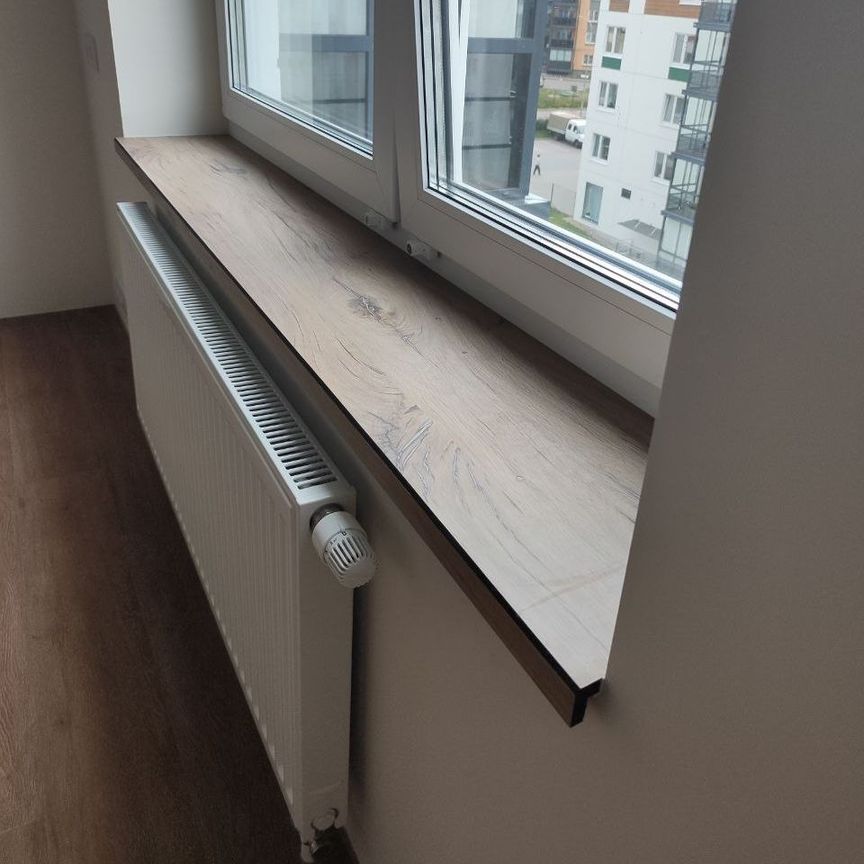 Подоконник из HPL компакт пластика с текстурой под дерево и подгибом, установленный под пластиковым окном в современном интерьере квартиры