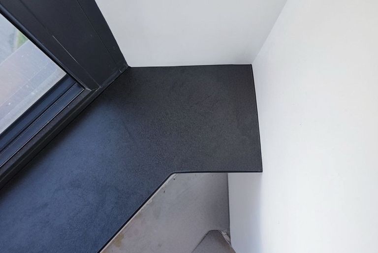 Подоконник сложной формы из HPL компакт пластика черного цвета, выполненный под углом для современного интерьера с панорамными окнами.