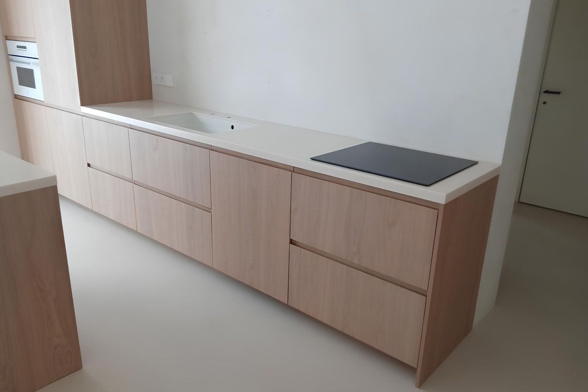 Белая столешница из акрилового камня с интегрированной мойкой и варочной панелью на кухне в современном стиле